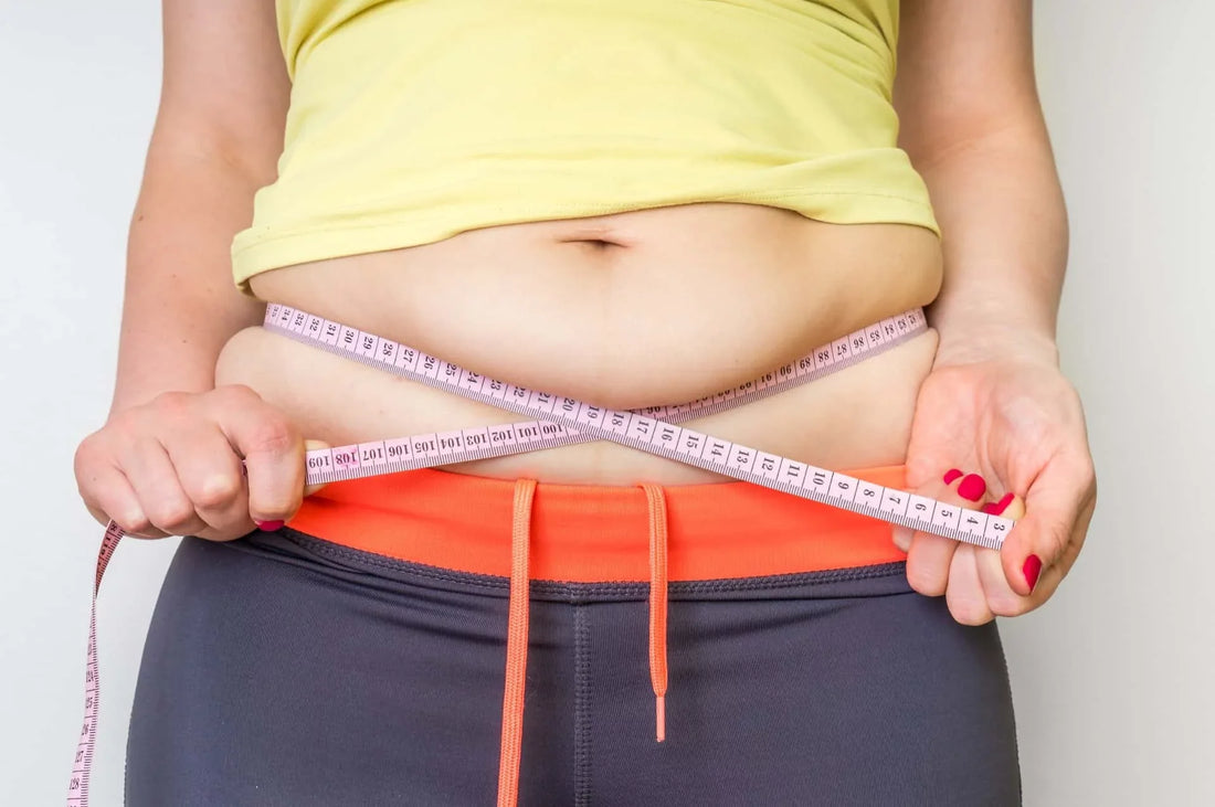 Woman holding her stomach looking frustrated, representing hormonal weight gain
